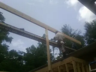 Carpenter setting a ridge beam over a new addition frame — Ice Dam Removal by Roofing Brothers in Alcove
