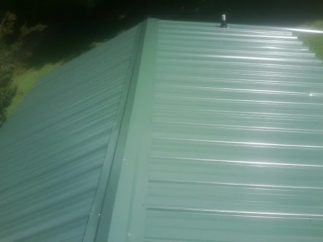 New green metal panels meeting at the ridge of a roof — Flat Roof Repair work by our crew in Alcove