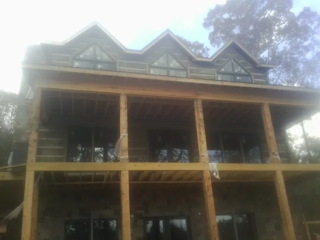 Dormers and porch framing on a large log home under construction — Roof Coating work by our crew in Alcove