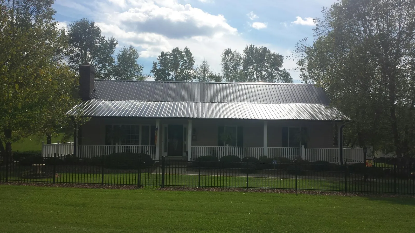 Gray metal roof on a brick ranch with a full width front porch — Gutter Guard Installation work by our crew in Alcove