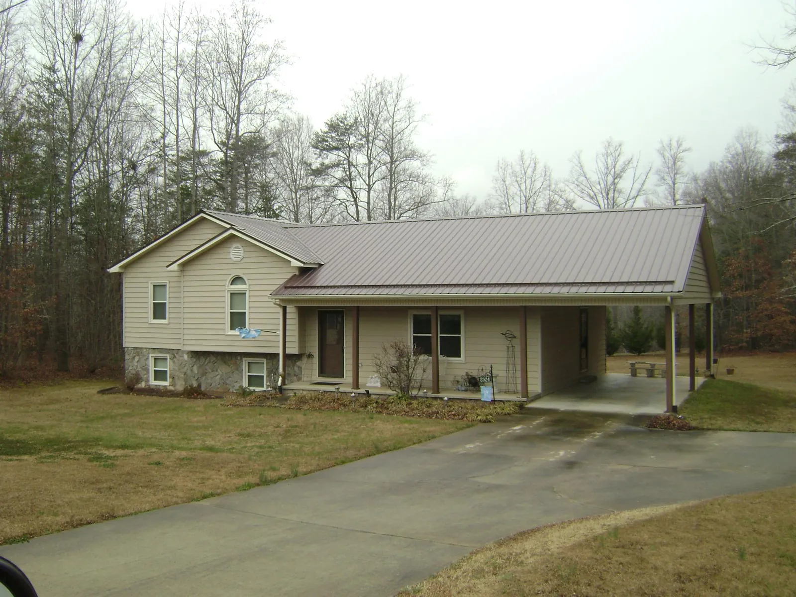 Brown metal roof on a tan split level home with an attached carport in Alcove
