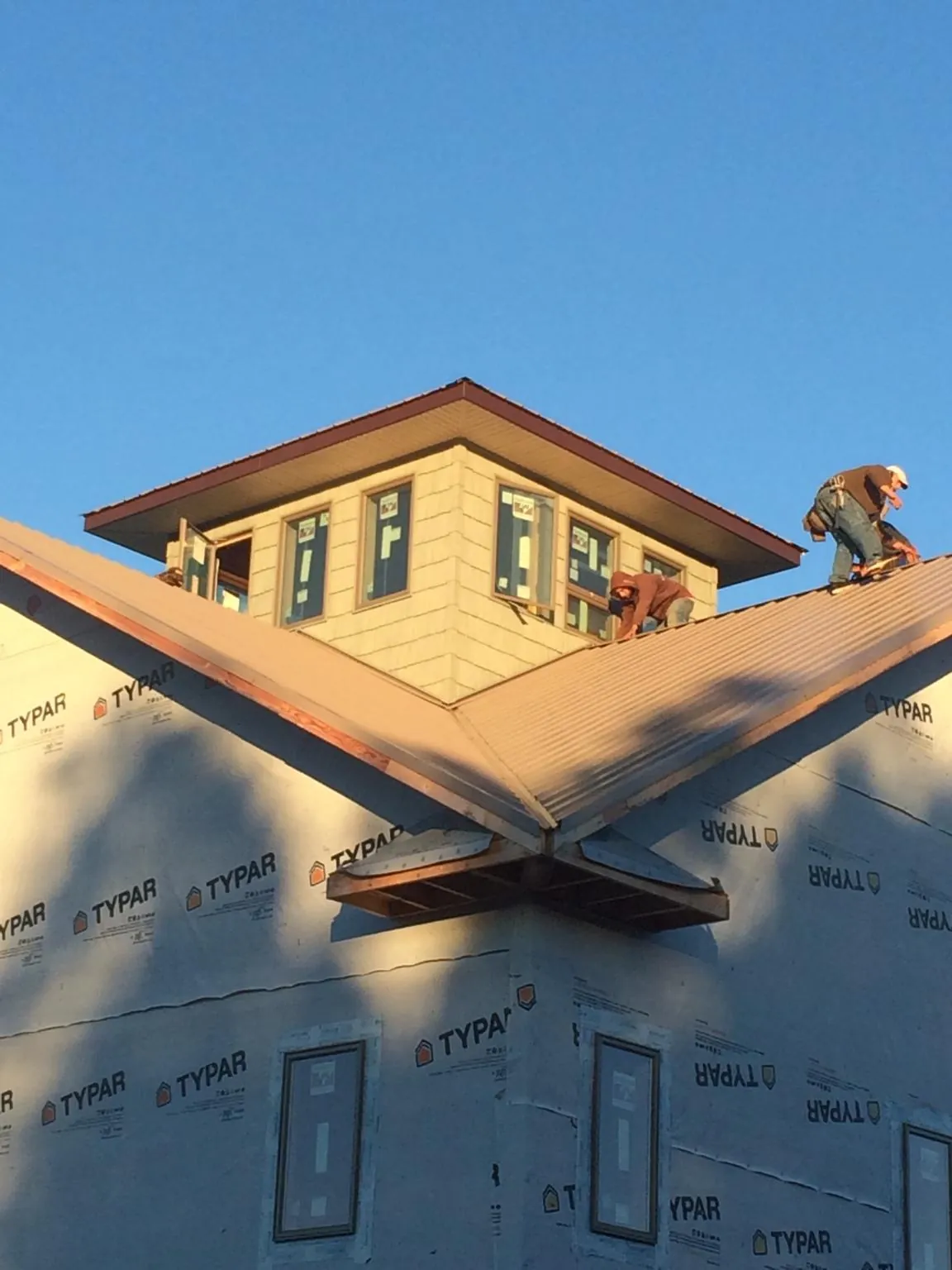 Roofers working around a rooftop cupola on a new metal roof at sunset — Roof Waterproofing in Alcove by Roofing Brothers